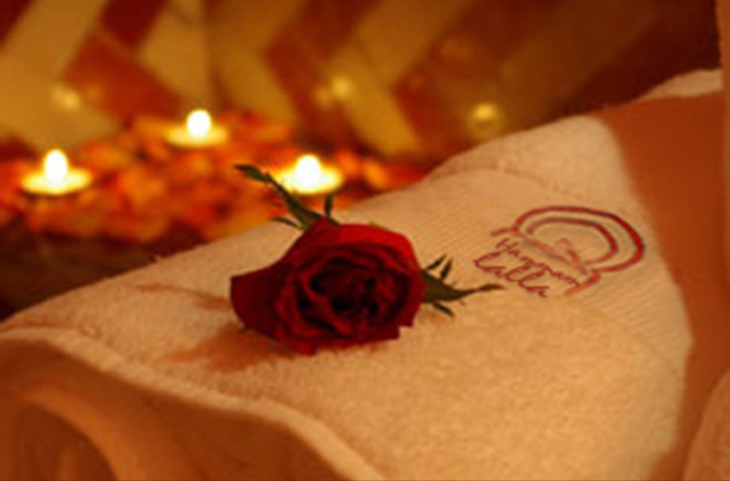 A picture of a red rose on the hammam's towel, with blurred candles behind
